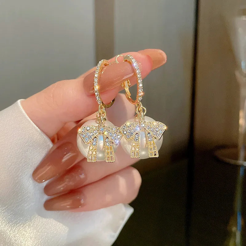 Pendientes de mujer con motivo de bola de Navidad, lazo y acentos de piedra