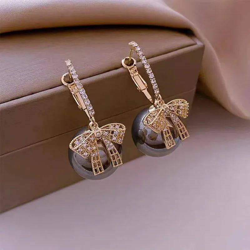 Pendientes de mujer con motivo de bola de Navidad, lazo y acentos de piedra
