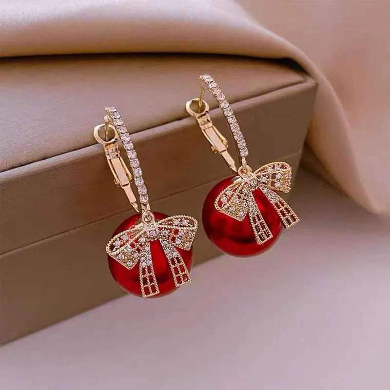 Pendientes de mujer con motivo de bola de Navidad, lazo y acentos de piedra