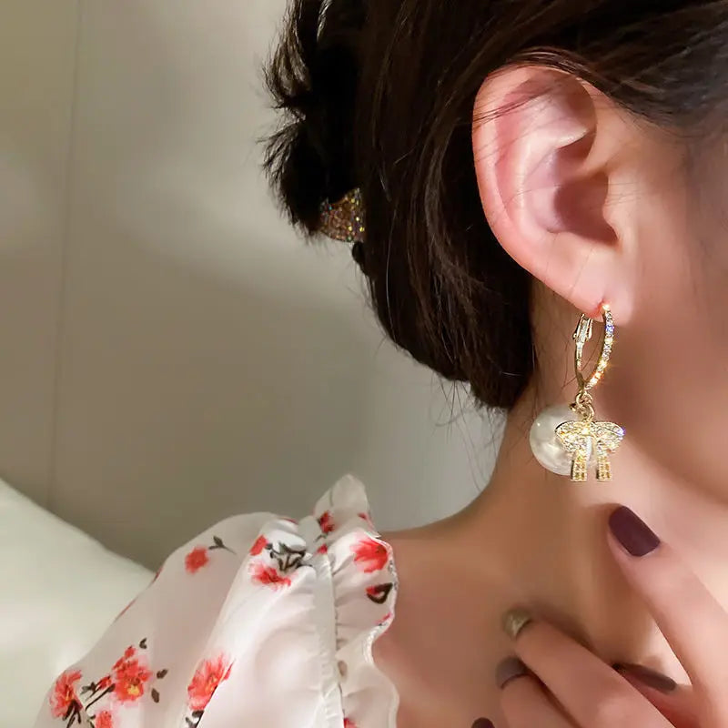 Pendientes de mujer con motivo de bola de Navidad, lazo y acentos de piedra