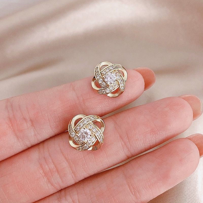 Elara – Pendientes Cruzados con Flor en Espiral